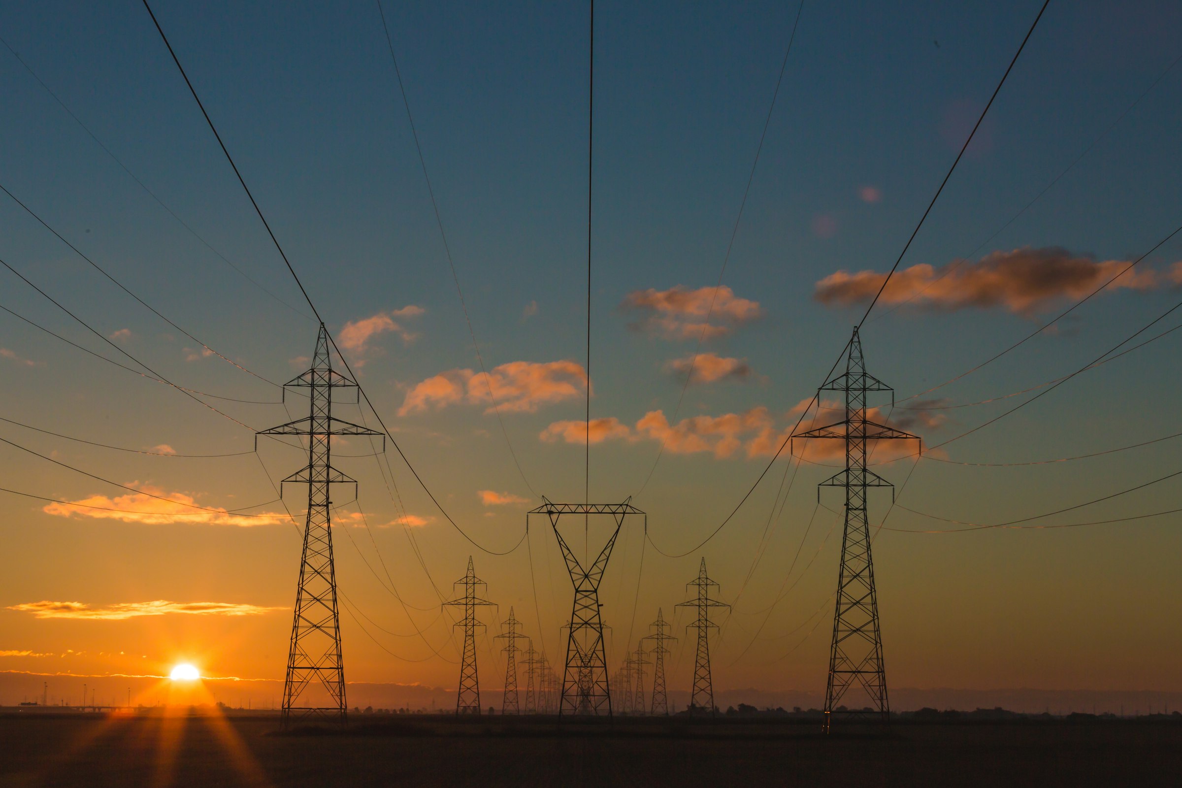 Transmission lines crossing open country at sunset